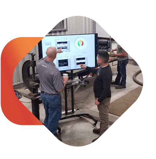 two men looking at a large screen with photos of data